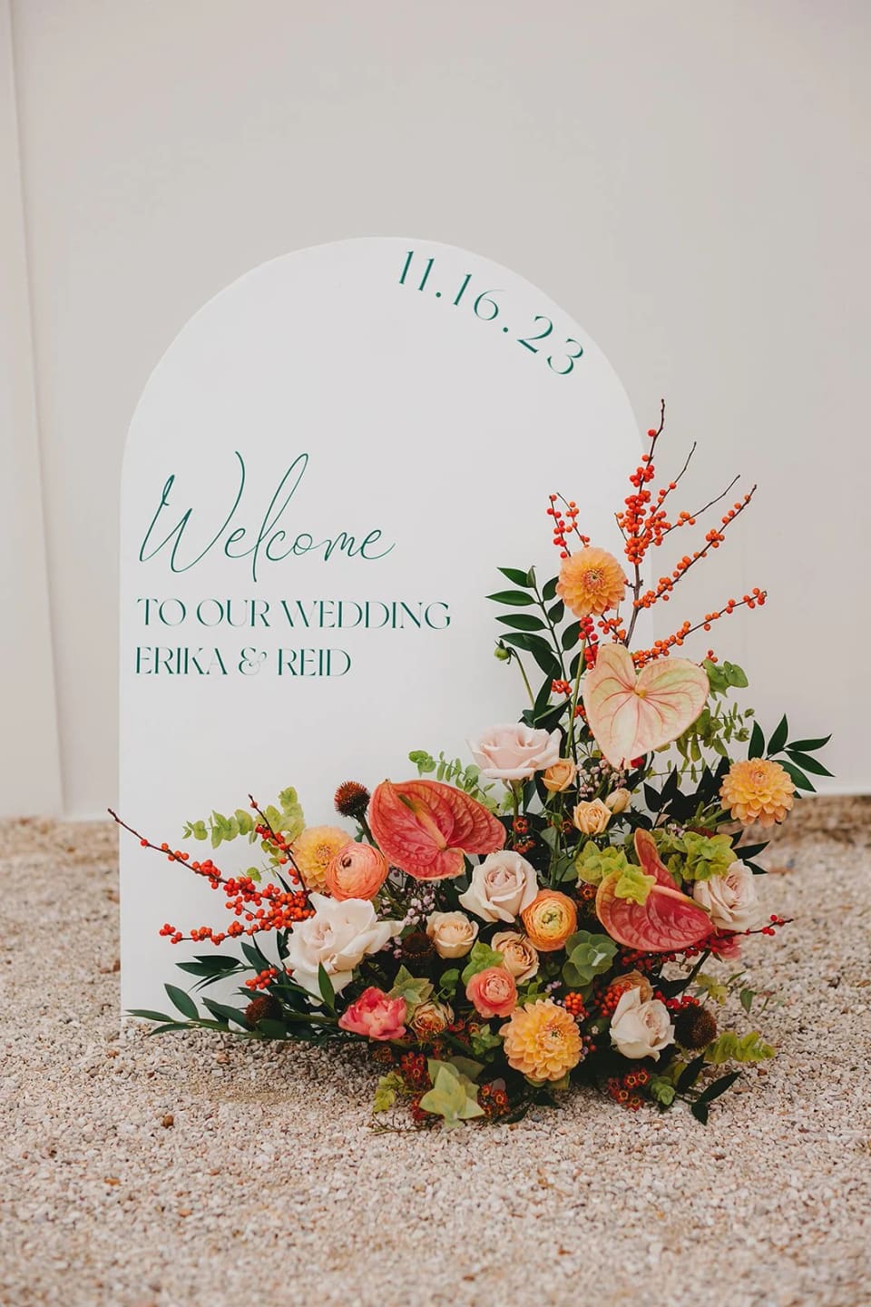 Welcome sign with vibrant coral arrangement at Kindred Oaks