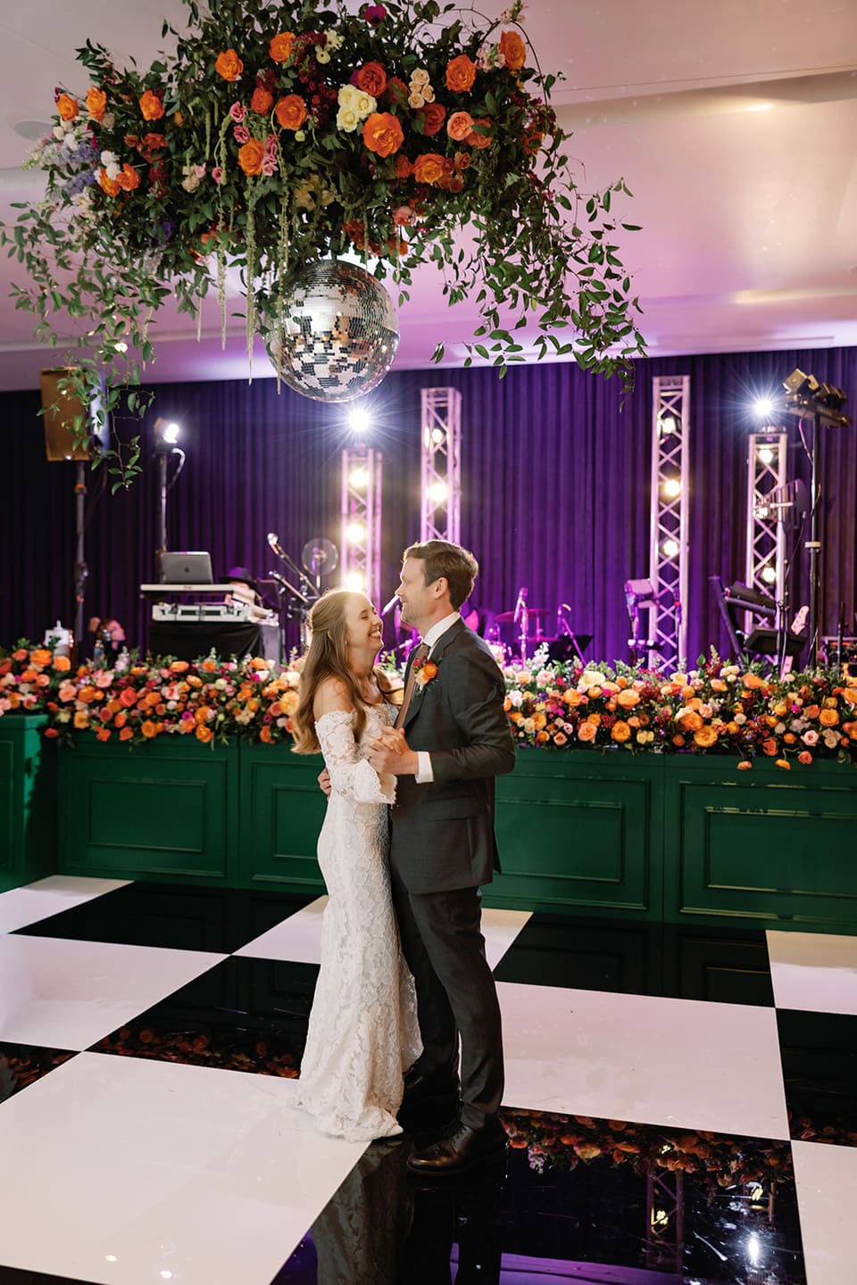 Bride and groom sharing a first dance under a disco ball and hanging floral installation at South Congress Hotel