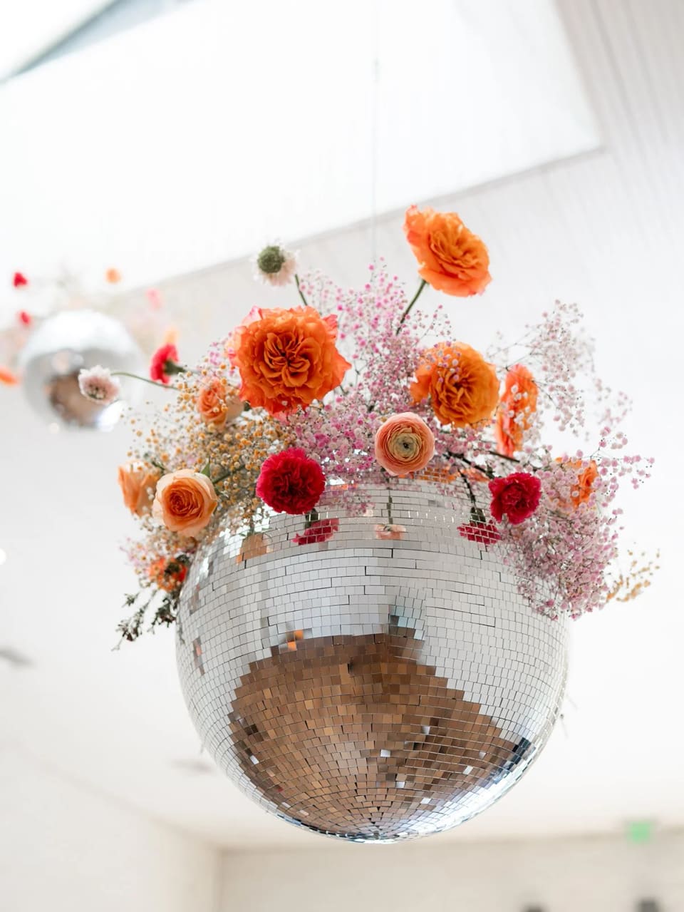 Disco ball crowned with orange and pink flowers at an event installation