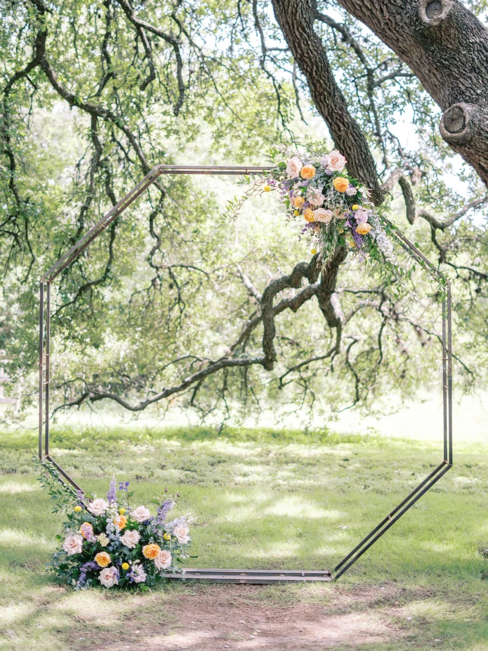 Octagonal ceremony arch with lavender and peach florals under an oak tree